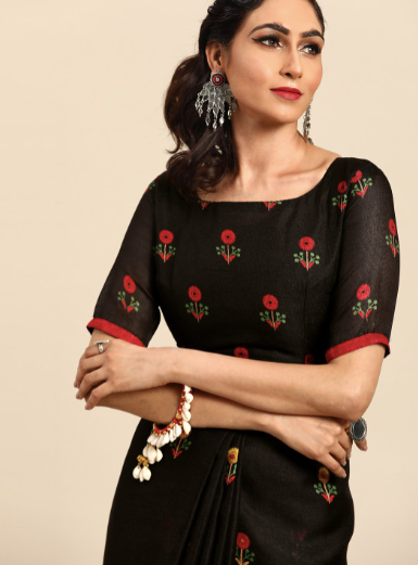 Woman wearing a black traditional outfit with red floral embroidery on a beige background