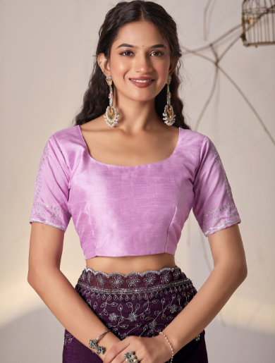 Woman wearing a pink blouse and purple skirt with a neutral background