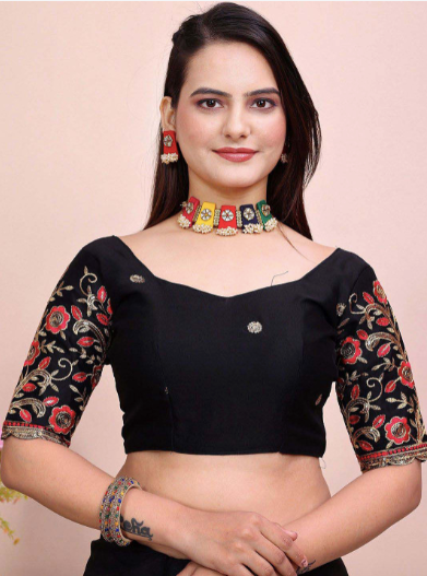 Woman wearing a black blouse with floral patterns and jewelry on a beige background