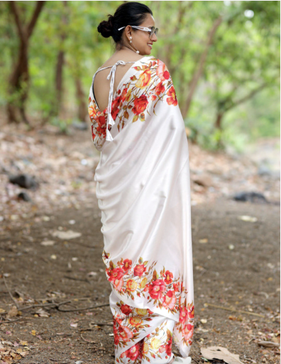 Woman wearing a white saree with floral patterns in a natural setting
