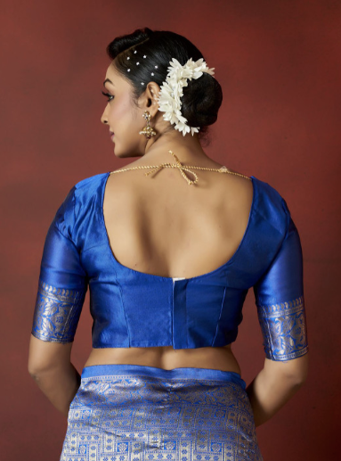 Woman wearing a blue traditional outfit with intricate designs on a red background
