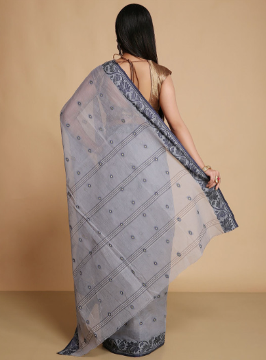 Woman wearing a light blue saree with a subtle pattern on a beige background