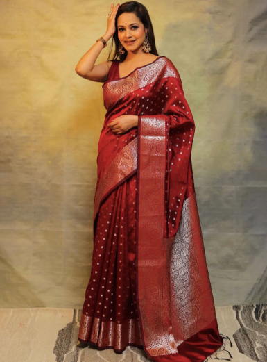 Woman wearing a red saree with a gold border against a neutral background