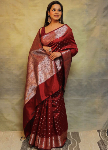 Woman wearing a red saree with a gold border against a neutral background