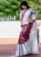 Woman in a white and pink saree with a floral pattern, standing outdoors.