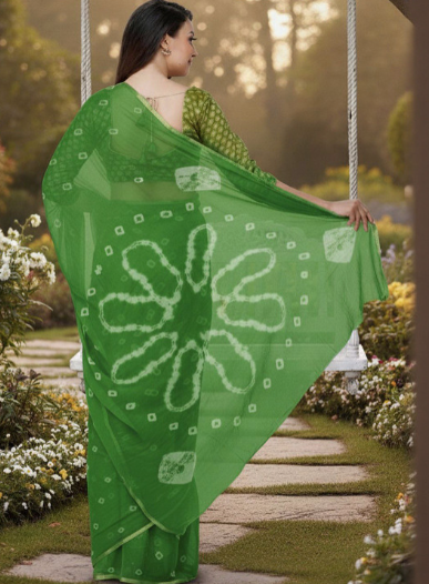 Woman in a green saree with white patterns standing in a garden.