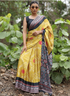 Woman wearing a yellow saree with a black blouse in a natural setting