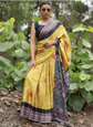 Woman wearing a yellow saree with a black blouse in a natural setting