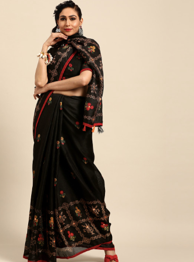 Woman wearing a black saree with intricate gold and red embroidery on a beige background