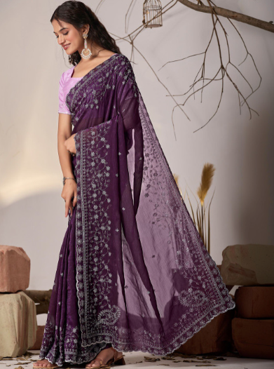 Woman wearing a purple saree with a white blouse in a minimalistic setting.