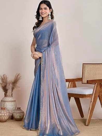 Woman wearing a blue saree in an indoor setting with decorative elements.