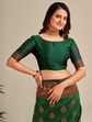 Woman wearing a green traditional outfit with gold patterns on a plain background