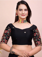 Woman wearing a black blouse with floral patterns and jewelry on a beige background