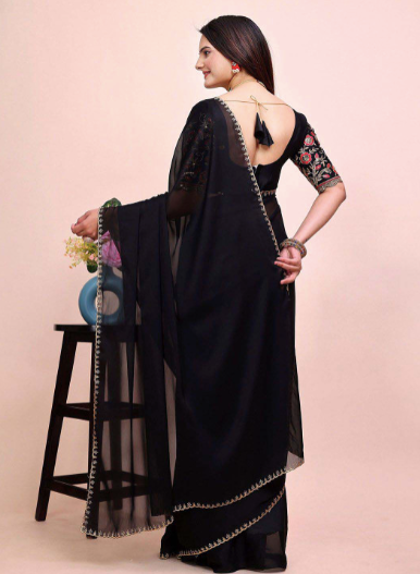 Woman wearing a black saree with floral embroidery on a light pink background