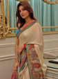 Woman in a colorful saree standing in front of a decorative mirror.