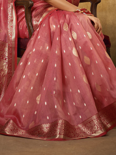 Pink saree with white polka dots and gold patterns on a chair.