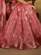 Pink saree with white polka dots and gold patterns on a chair.