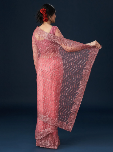 Woman wearing a pink saree with a dark background