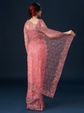 Woman wearing a pink saree with a dark background