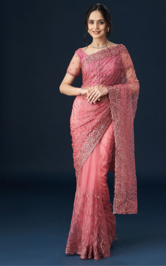 Woman wearing a pink saree with a dark background