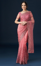 Woman wearing a pink saree with a dark background