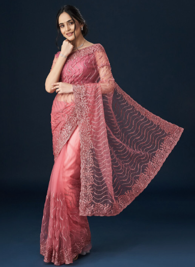 Woman wearing a pink saree with a dark background