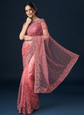 Woman wearing a pink saree with a dark background