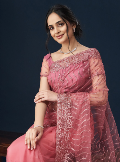 Woman wearing a pink traditional outfit with intricate designs on a dark background