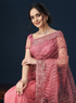 Woman wearing a pink traditional outfit with intricate designs on a dark background