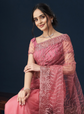 Woman wearing a pink traditional outfit with intricate designs on a dark background