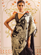 Woman wearing a black and white patterned saree with a decorative background