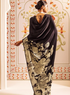 Woman wearing a black floral-patterned dress in an ornate room.