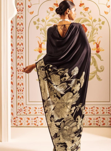 Woman wearing a black floral-patterned dress in an ornate room.
