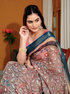 Woman wearing a traditional saree with floral patterns indoors.