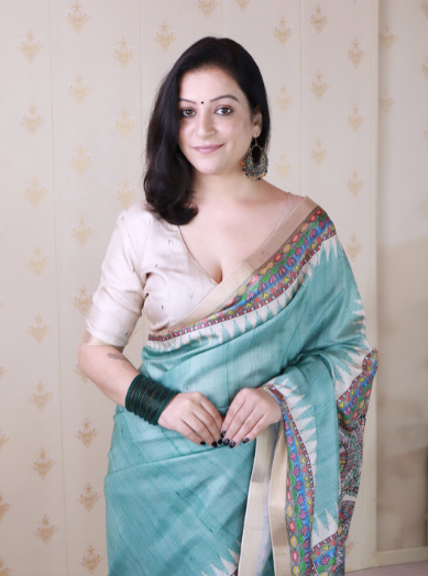 Woman wearing a light blue saree with a beige blouse against a neutral background