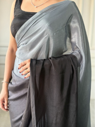 Person wearing a gray saree with a plain background