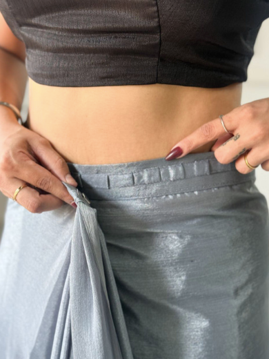 Person wearing a black top and gray pants, adjusting the waistband.