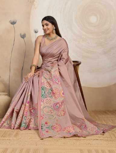 Woman wearing a pink saree with floral patterns against a neutral background