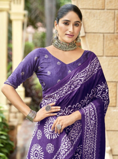Woman wearing a purple saree with white patterns in an outdoor setting