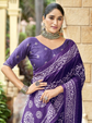 Woman wearing a purple saree with white patterns in an outdoor setting