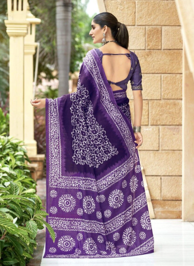 Woman wearing a purple saree with white patterns, standing outdoors.
