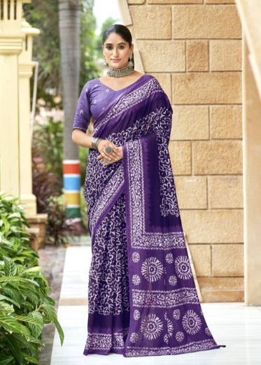 Woman wearing a purple saree with white patterns standing outdoors.