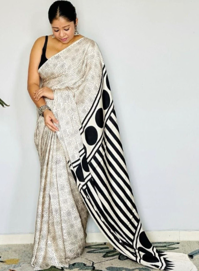 Woman wearing a saree with a black and white pattern on a plain background