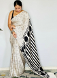 Woman wearing a saree with a black and white pattern on a plain background