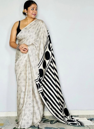 Woman wearing a saree with a black and white pattern on a plain background