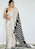 Woman wearing a saree with a black and white pattern on a plain background