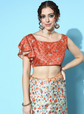 Woman wearing a red patterned top and floral skirt against a blue background