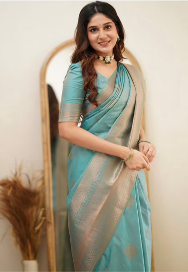 Woman wearing a blue saree with a beige border in front of a mirror.
