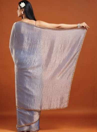 Woman holding a saree against an orange background