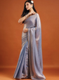 Woman wearing a silver saree against an orange background